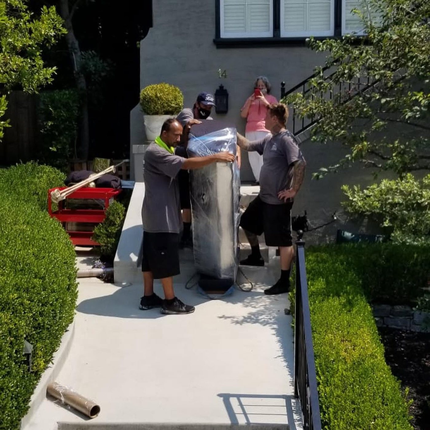 OCD Moving Services crew carefully carrying a wrapped piece up a walkway at a customer's home