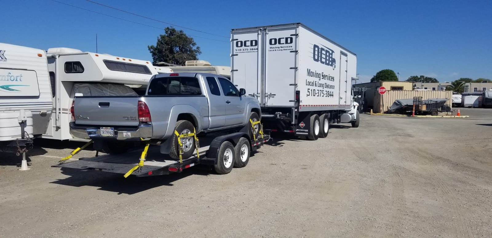 OCD Moving Services branded truck with a customer's vehicle loaded for transport