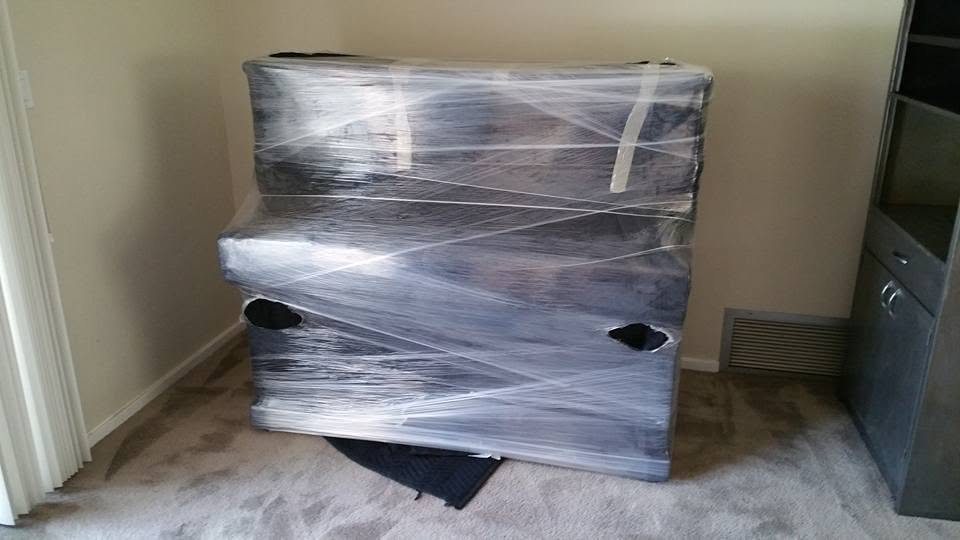 A piano fully shrink-wrapped and padded by OCD Moving Services for safe transport